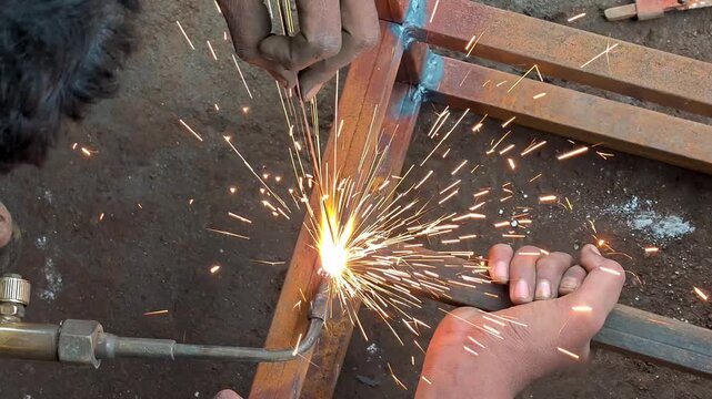 Welder gas welding metal square pipe frame with torch in workshop. Gas welding process
