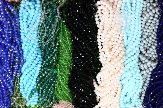 Close up full frame background of colorful faceted glass bead strands arranged in vertical rows. Craft supply texture for DIY jewelry making concepts and creative retail backgrounds.