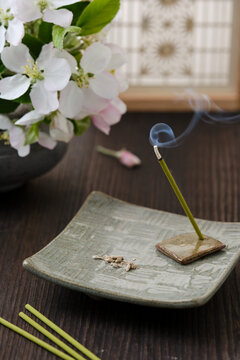 Traditional japanese incense holder with burning incense and white flowers