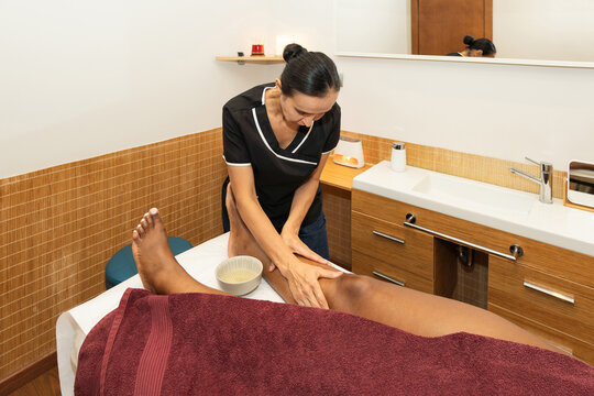 Therapist massaging woman's leg in a wellness center
