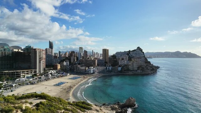 Aerial panorama of residential apartment blocks in Cala de Finestrat, Benidorm, with the coastline and Poniente Beach in the distance, from around 50 meters altitude, Costa Blanca, Alicante, Spain, mo