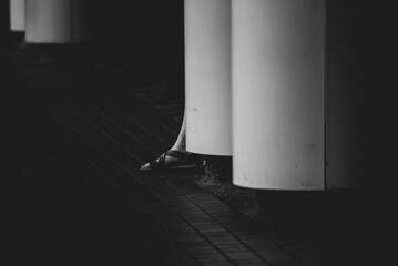 Obraz premium Black and white architectural column beside tiled pavement creates stark urban scene with dramatic shadow, texture, and minimalist geometric composition