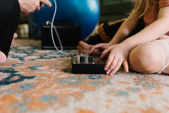 Child playing with a small synthesizer on a patterned rug indoors.