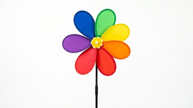 Vibrant rainbow pinwheel toy featuring colorful plastic petals attached to a simple black rod on white background