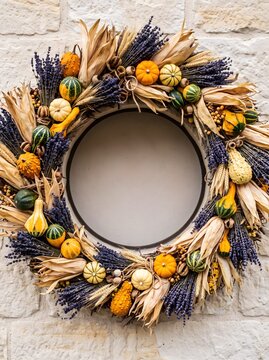 Autumn harvest wreath with wheat and pumpkins on a stone wall