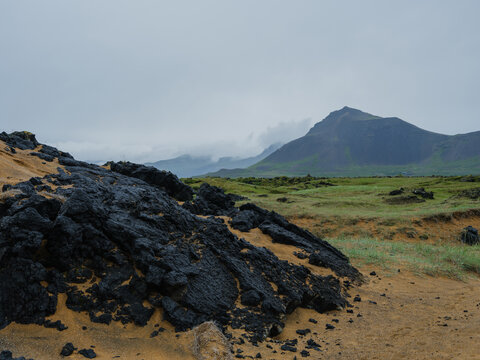 Rugged volcanic rock formation near grassy meadow in Iceland