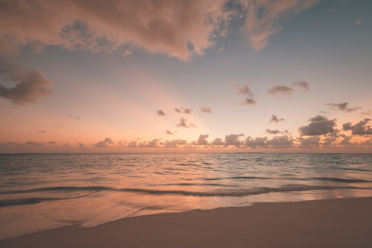 Dreamy pastel sunset calm sea soft glowing golden clouds sandy shore evening quiet summer coastal horizon. Peaceful sunset travel scene. Romantic relaxing meditation wellness coastal background 