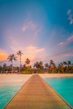 Breathtaking wooden jetty pier stretching pastel sunset turquoise lagoon overwater villas tropical island resort. Perfect summer vacation travel scene. Luxury romantic wanderlust relaxation background