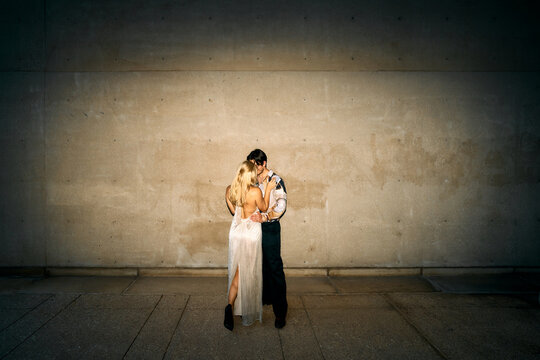 Couple embracing against a concrete wall