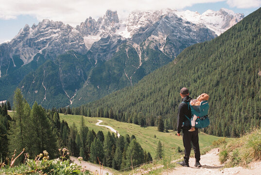 Anonymous man with baby in a carrier in front of the mountains