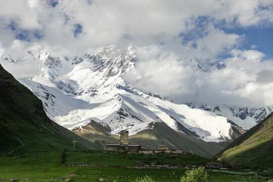 Lamaria Church and Svan tower beneath snowy Caucasus mountains