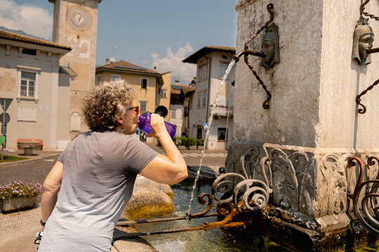 Senior cyclist drinking water at fountain in Italy, europe