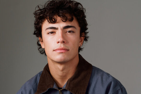 Young Man With Curly Hair Posing Against a Plain Background