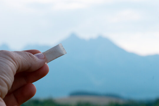 hand holding nicotine pouch snus tobacco product against mountain landscape background with copy space for banner design concept of lifestyle, habit, health, marketing, retail