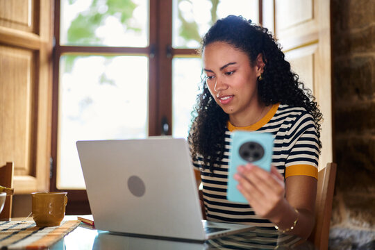 Woman working online at home using laptop and phone