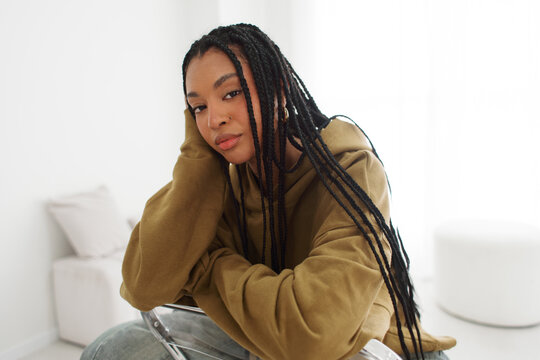 Woman With Braids Sitting on Chair in Bright Room