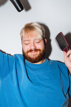 Young Man Styling Hair with Dryer and Hair Brush
