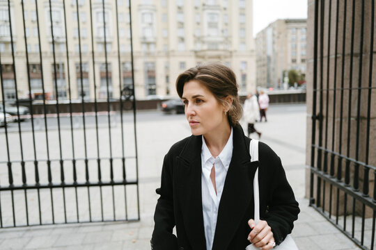 Woman Walks Confidently Through an Urban Gate on a Cloudy Day