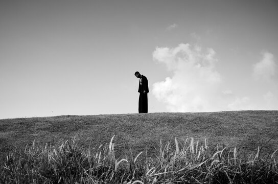 Solitary figure standing with head lowered
