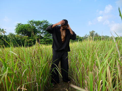 Man walking through tall grass with reflective expression