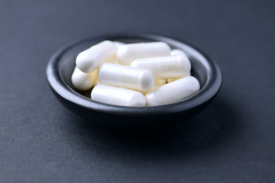 Creatine capsules on dark paper background. Soft focus. Close up. Copy space