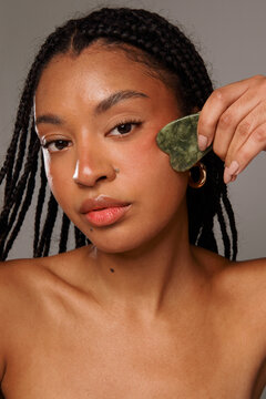 Woman Holds Jade Facial Tool in Indoor Setting