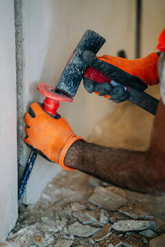 Detail of hammer striking chisel on wall