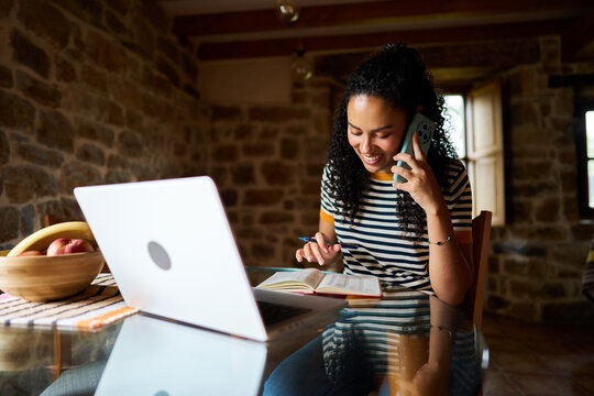 Young woman remote working at home talking on phone