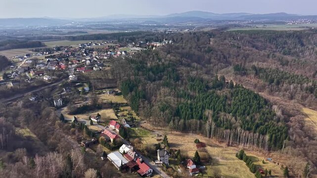 Aerial Hamlet Nestled Beside Woodland And Open Meadows Showing Cottages, Curving Lanes, Tree Clusters