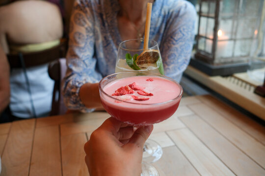 Friends toasting with colorful drinks at restaurant