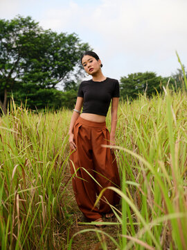 Contemporary woman standing in tall grass beneath open sky