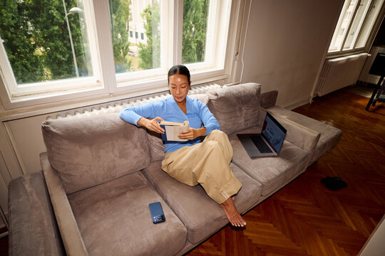 Woman reads a book on a couch