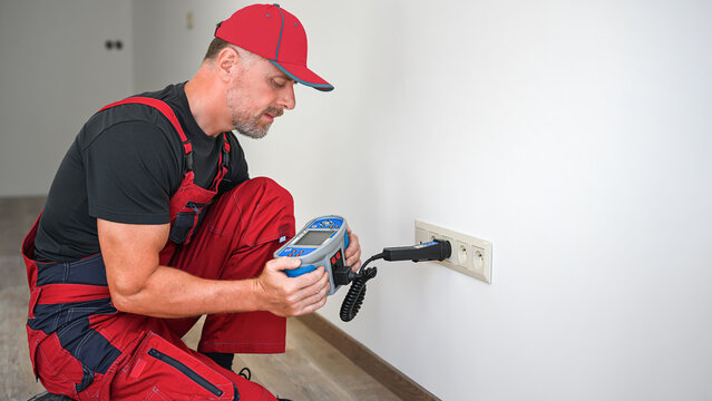 A electrician using multifunction tester for revision of electrical circuits . Initial verification and periodic inspection and testing of electrical installations.
