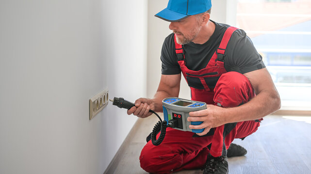 A electrician using multifunction tester for revision of electrical circuits . Initial verification and periodic inspection and testing of electrical installations.