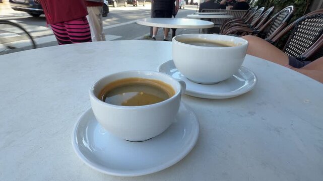Two Cups of Coffee on a White Table at an Outdoor Cafe