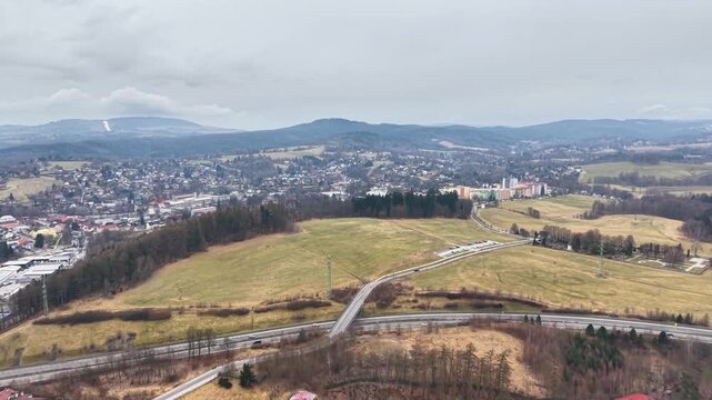 Aerial Winding Country Road Through Fields And Valley Showing Bridge, Rolling Meadows, Distant Town, Route