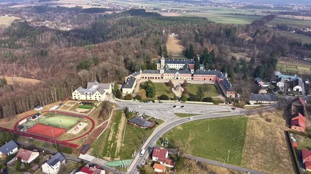 Aerial View Of Historic Estate And Forest, Cinematic Drone Circle Exposes Castle Wings, Chapel Tower, Formal