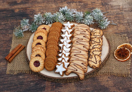 Traditionelle Weihnachtspl&auml;tzchen wie Zimtsterne und Engelsaugen sortiert auf einer rustikalen Baumscheibe.