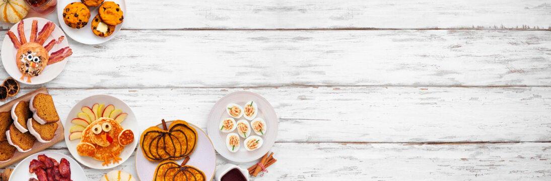 Fun Thanksgiving or fall breakfast or brunch foods. Above view corner border on a white wood banner background. Pumpkin spice pancakes, loaf, muffins, turkey shaped pancakes and pastry. Copy space.
