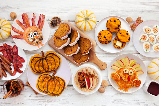 Fun Thanksgiving or fall breakfast or brunch foods. Top view table scene on a white wood background. Pumpkin spice pancakes, loaf, muffins, turkey shaped pancakes and pastry.