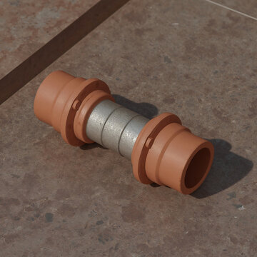A close-up view of a mechanical pipe coupling with terracotta colored ends and a metallic center section resting on a brown tiled surface