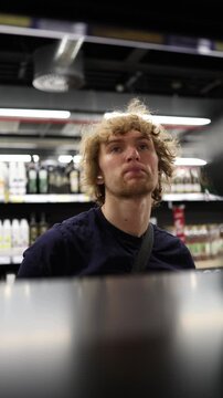 Vertical screen supermarket worker restocks products on store shelves keeping merchandise organized and available for customers while working inside a large grocery store