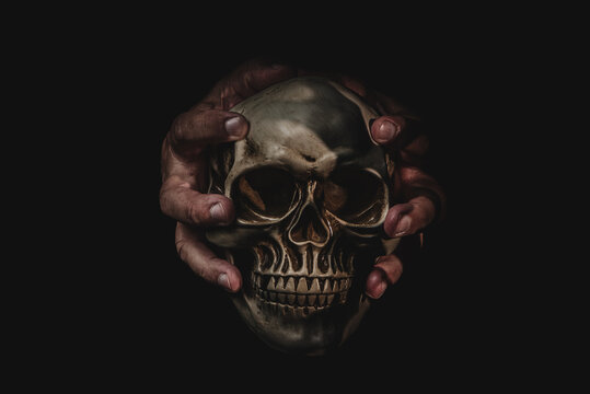 Human hands holding a skull on dark background.Memento mori.