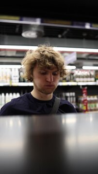 Vertical screen shopper finds a favorite product on supermarket shelf and reaches for it with confidence after recognizing the item he likes during routine shopping trips