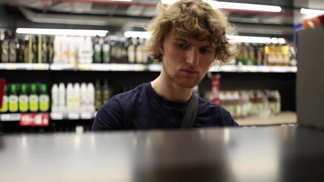 Shopper sees half empty supermarket shelves while choosing groceries reflecting low stock product shortages reduced selection and changing retail supply conditions there
