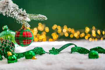 Naklejka premium A Christmas background featuring green velvet baubles, a red and green plaid ornament, and a snowflake wrapped in glittering ribbon on snow, set against deep green with twinkling lights.