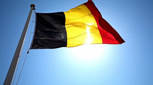 National flag of belgium waving against a clear blue sky