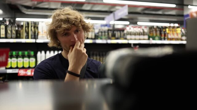 Shopper hesitates over whether to buy a product while comparing his options and resisting impulse spending before finally deciding to take the item from the store shelves