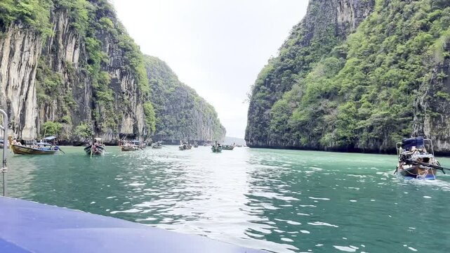 Phi Phi Island limestone cliffs above turquoise Andaman Sea near Phuket, Thailand, with tour boats along tropical coast, showcasing dramatic karst scenery, island travel and marine adventure landscape