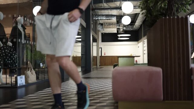 Male sitting in shopping mall stands up and walks away after resting on bench showing motivation action decision and active lifestyle in modern public indoor space to act